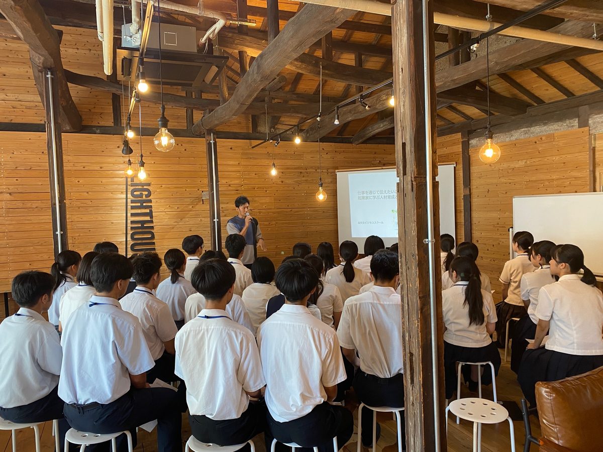 古民家の梁の下でスツールに座り、講師の話を聞く高校生たち。LIGHTHOUSEでのセミナー開催の様子
